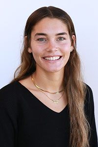 woman with brown hair wearing a black shirt and gold necklaces