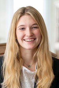 white woman with blonde hair wearing a white short and dark jacket