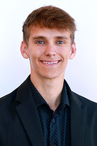 man with blonde hair wearing a dark dress shirt and suit jacket