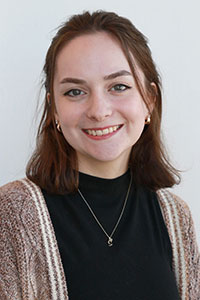 woman with dark shoulder length hair wearing a black turtle neck and sweater