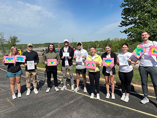 group of students standing on parking lot holding crafts from event