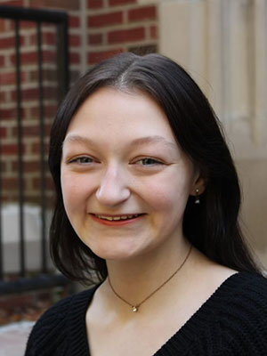 white woman with dark hair wearing a dark shirt sitting on steps